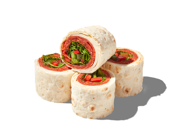 Four pinwheel sandwiches with meat and lettuce. 